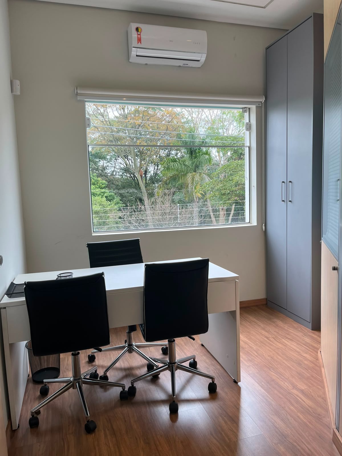 Escritório mobiliado com janela e vista para árvores