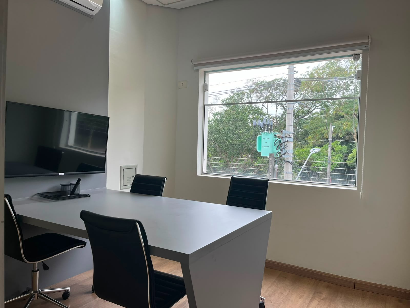 Sala de reunião com mesa branca e cadeiras pretas