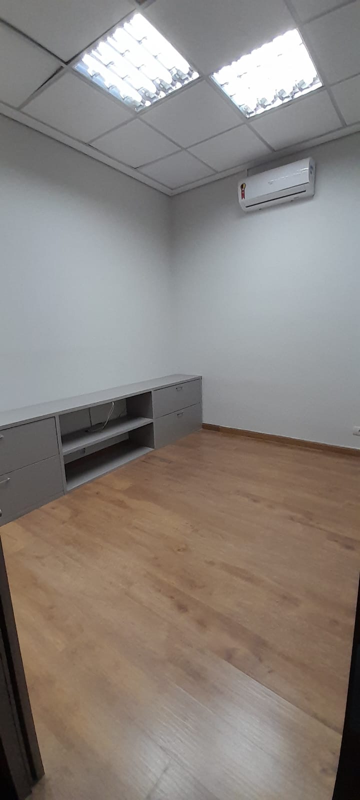 Sala vazia com piso de madeira e armários baixos